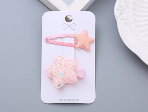 Close-up of glitter pink star hair clips with handmade lettering on packaging card