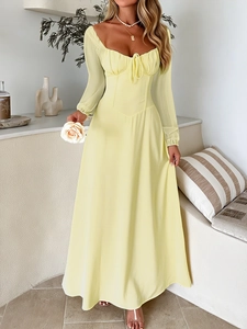 Elegant pale yellow maxi dress with square neck and lace-up detail in a stylish room