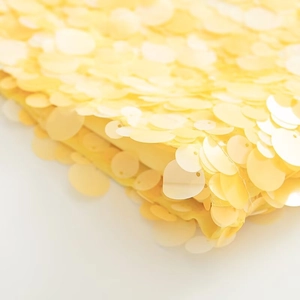 Macro shot of vibrant yellow sequins on the fabric showing metallic luster and texture