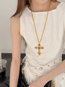 Vue détaillée d'un pendentif croix vintage doré avec pierres ambrées sur blanc