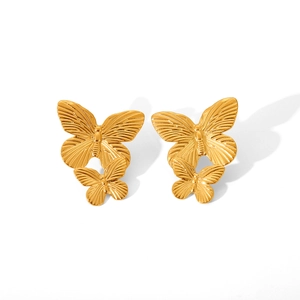 Detail of golden double butterfly earrings with layered metal texture on white background