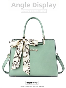 Front view of mint green trapezoid handbag with decorative silk scarf on handle