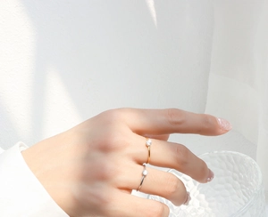 Close-up of minimalist gold and silver rings with single diamond worn by a hand on a glass