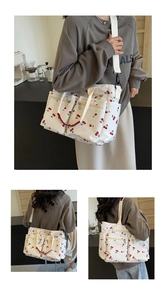 Detailed view of canvas tote bag with red cherry print featuring multiple zipper pockets