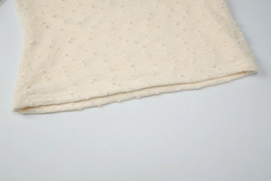 Detailed macro view of beige knit fabric texture and high-quality hem stitching