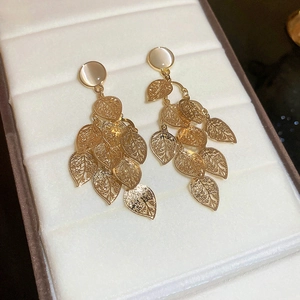 Detail showing golden opal earrings with hollow leaves and long elegant tassels