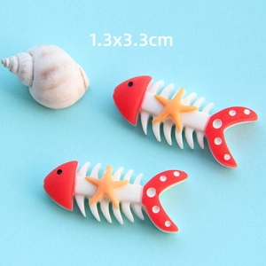 Dettaglio di due accessori in resina a forma di lisca di pesce con misura 1,3x3,3cm