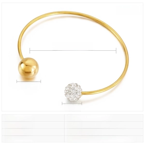 Détail d'un jonc en acier doré en C montrant un diamètre de 63 mm et une boule de strass
