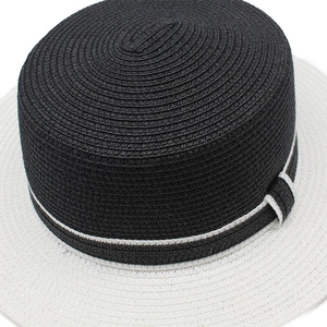 Detail of flat-top straw hat featuring contrast black woven crown and white brim trim