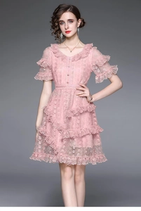Detail of pink lace dress showing intricate crochet fabric and layered ruffle hemline