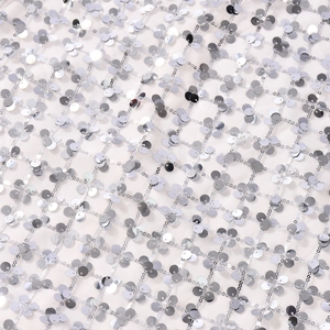 Gros plan détaillé de paillettes argentées sur tissu résille blanc à motif losange