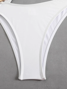 Close-up of white swimwear fabric featuring sheer mesh panels and decorative pearl detail
