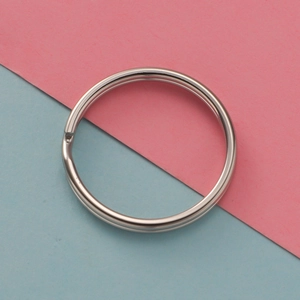 Detail view of a 25mm polished stainless steel flat split key ring on a pastel background