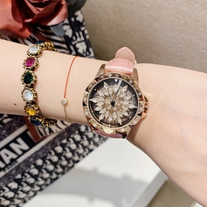 Detail of rose gold watch with crystal flower dial and pink leather strap worn on wrist