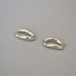 Detalle macro de pendientes minimalistas plateados en forma de U con acabado metálico