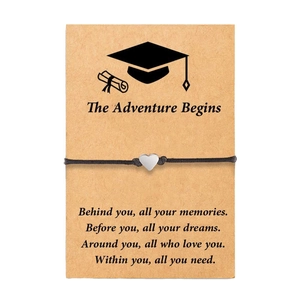 Close-up of heart charm bracelet on kraft paper card with graduation adventure message