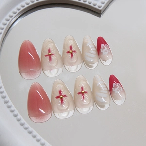 Pink blush gradient press-on nails with 3D flower and cross patterns on an embossed plate