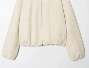 Detail of the elastic hem and zipper on a cream textured fleece jacket for women