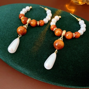 Detail of vintage teardrop pearl earrings with resin beads on green velvet display