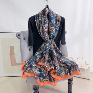 Navy blue paisley printed silk scarf with orange borders draped on a chair