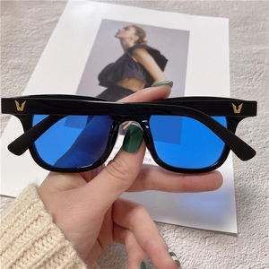 Detail of black square frame sunglasses with blue lenses and gold metal V logo