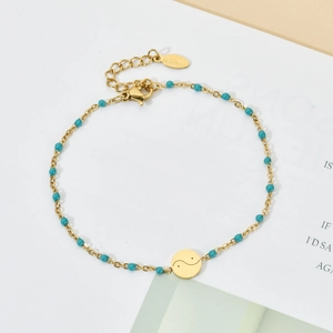 Detail of gold stainless steel bracelet with green beads and Yin Yang tai chi charm
