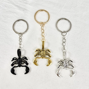 Detailed view of alloy scorpion keychains in black, gold, and silver metallic finishes