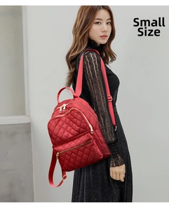Side view of small red quilted backpack with gold zippers worn by a model