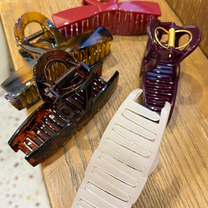 Detailed view of large acetate hair claws in various colors with elegant golden buckle accents