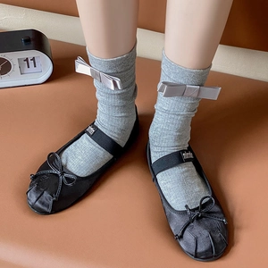 Detail of grey socks with silver bows paired with black satin Mary Jane shoes and strap