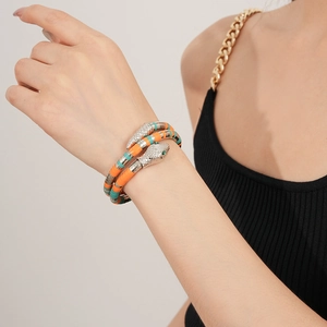 Detail of silver snake wrap bracelet with orange and turquoise enamel on female wrist