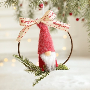 Knitted Christmas gnome ornament with wooden ring and pine needles on festive background