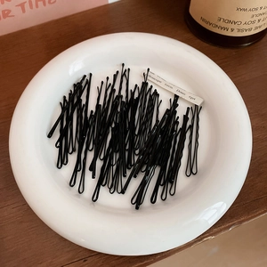 Détail de barrettes à cheveux en métal noir à structure ondulée sur une assiette