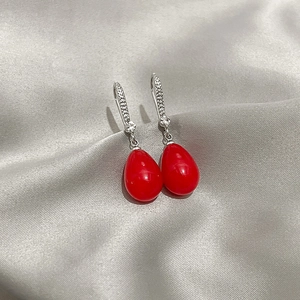 Close-up of elegant red teardrop earrings with silver hooks and sparkling zircon accents