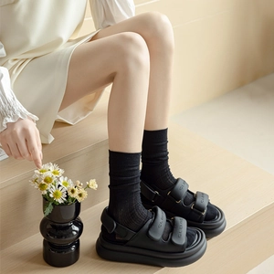 Women's black platform sandals with velcro straps worn with trendy sheer crew socks