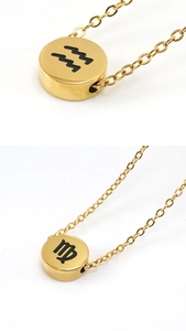 Detailed close-up of gold stainless steel circular pendants with zodiac sign engravings