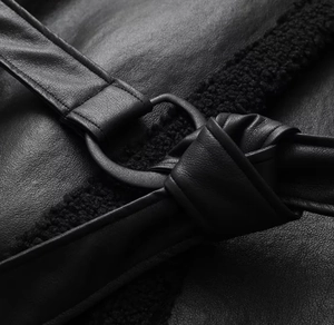 Detail of premium black faux shearling coat featuring leather texture and metal D-ring buckle