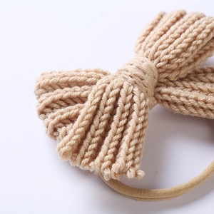 Soft knitted bow baby headband in beige wool on a nylon band for newborns