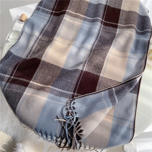 Detail of soft plaid scarf with tassels in brown and blue hues for winter warmth