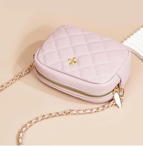 Detailed view of pink quilted leather cross-body bag with golden chain and floral clasp