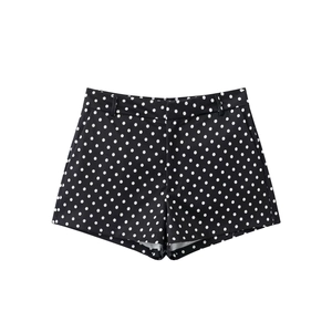Dettaglio piatto di pantaloncini neri da donna con motivo a pois bianchi su sfondo bianco