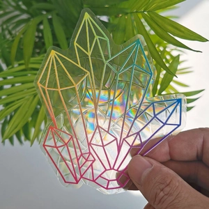 Close-up of holographic crystal suncatcher sticker with rainbow light effect on glass