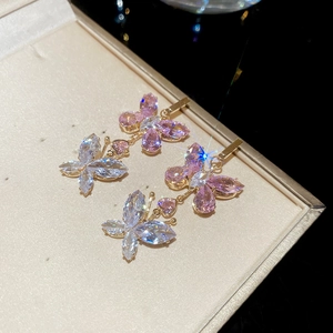 Macro detail of butterfly earrings with pink zircon on gold base in a jewelry box