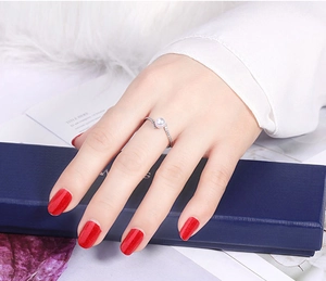 Detail of silver hollow ring with a central pearl and diamonds on a person's finger