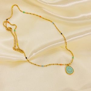 Detail of gold stainless steel necklace featuring colorful beads and blue smiley face charm
