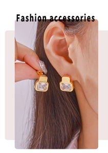 Close-up of geometric gold-plated earrings with emerald-cut cubic zirconia stones on model