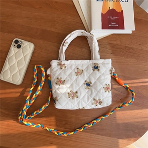 Overhead view of a quilted mini bag with bear print on a wooden desk with accessories