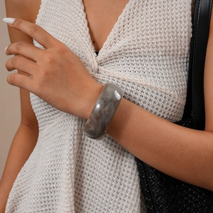 Dettaglio di un grosso bracciale in resina marmorizzata grigia per uno stile elegante