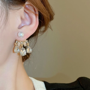 Detailed side view of pearl and drop crystal earrings worn by a model in soft light