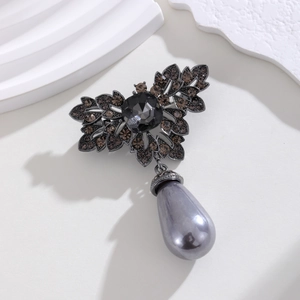 Detailed close-up of a vintage gunmetal flower brooch with dark crystals and a pearl drop